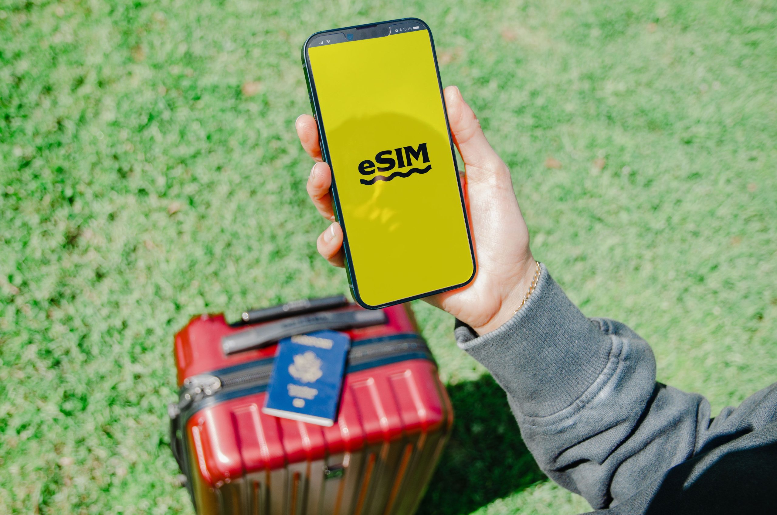 Voyageur avec téléphone eSIM près valise rouge